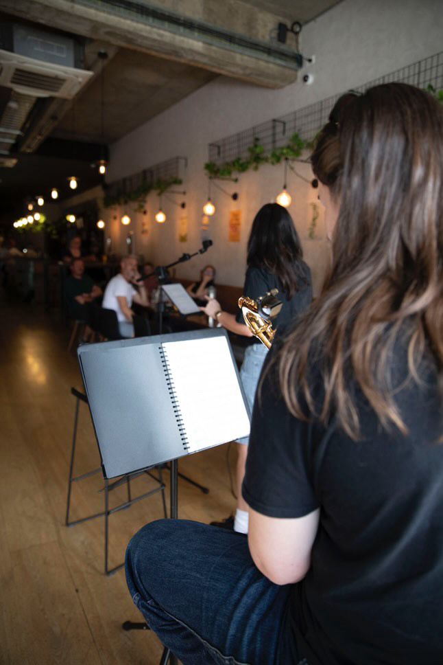 Interior of Hopheads Yarraville craft-beer bar showing the tap wall, patrons enjoying beers, and warm ambient lighting.